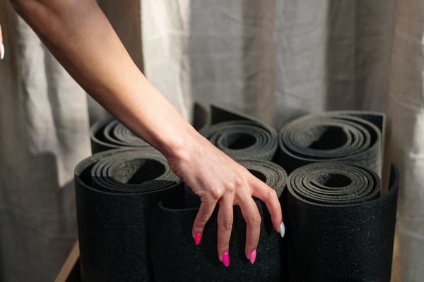 Close up of yoga equipment and a person stretching on a mat.